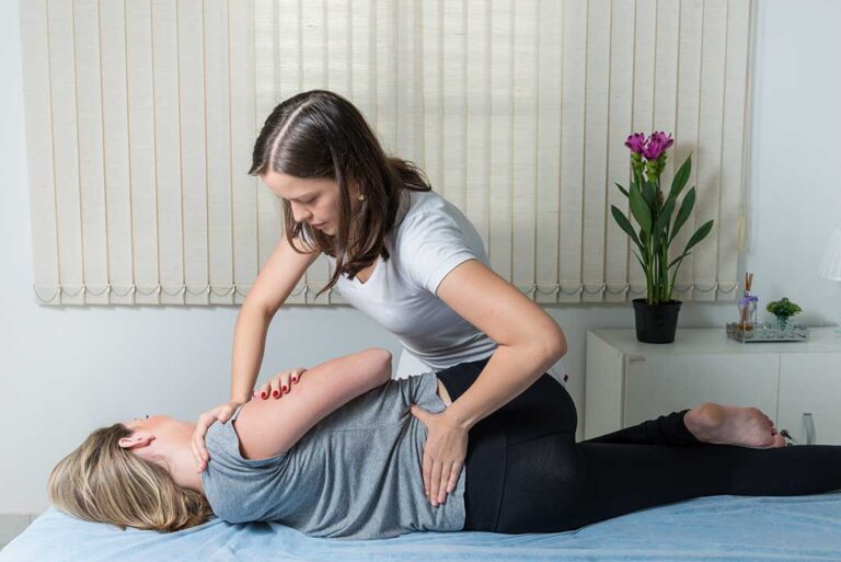 Person gently stretching a hand while a knee and spine anatomy model sit nearby.